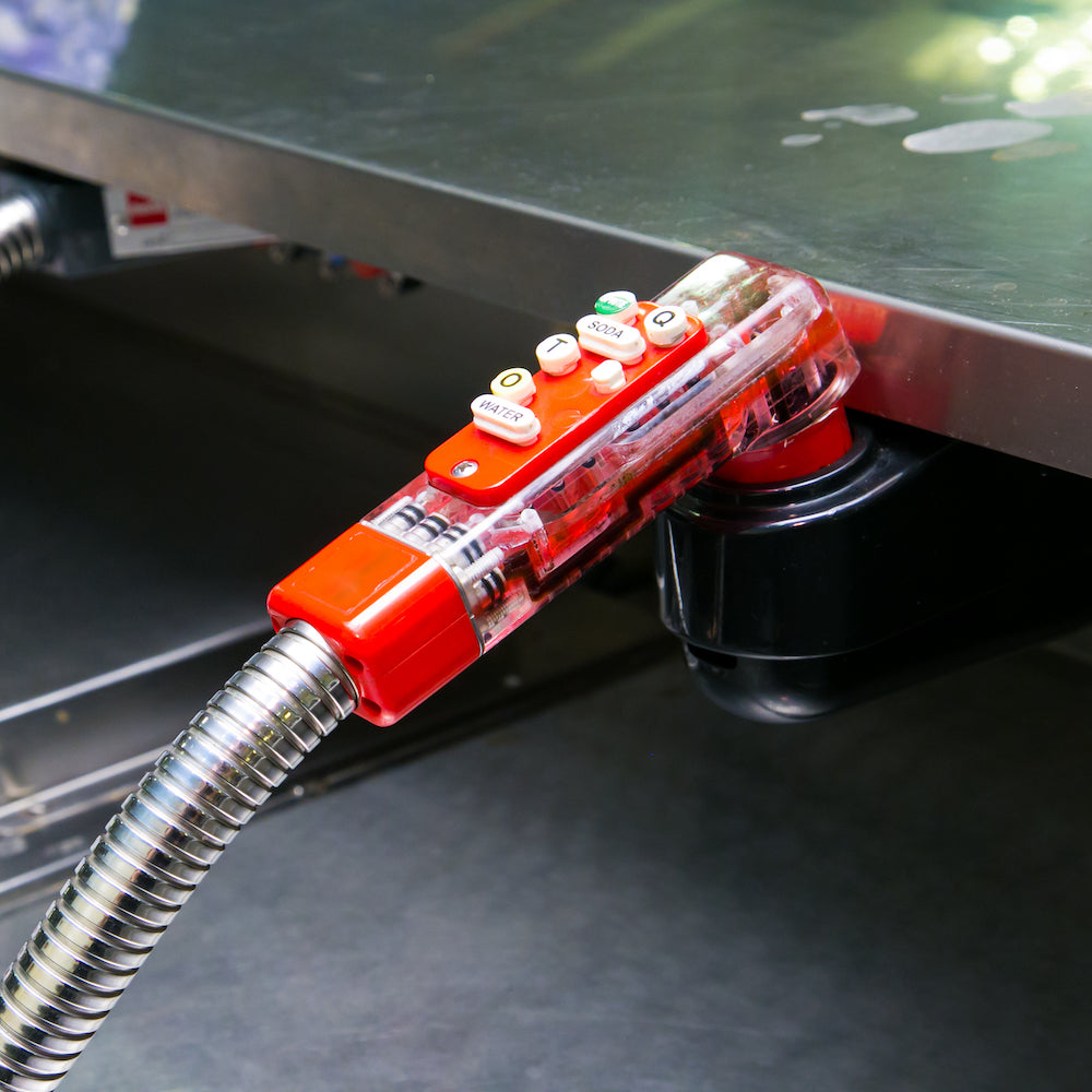 A transparent red handle with buttons on a flexible metal hose is attached to a metal surface, reminiscent of an Extra Spicy Mule toast. It features numbered and symbol-labeled buttons for precision, akin to perfecting Top Hat Provisions Top Hat Extra Spicy Ginger Beer Moscow Mule.