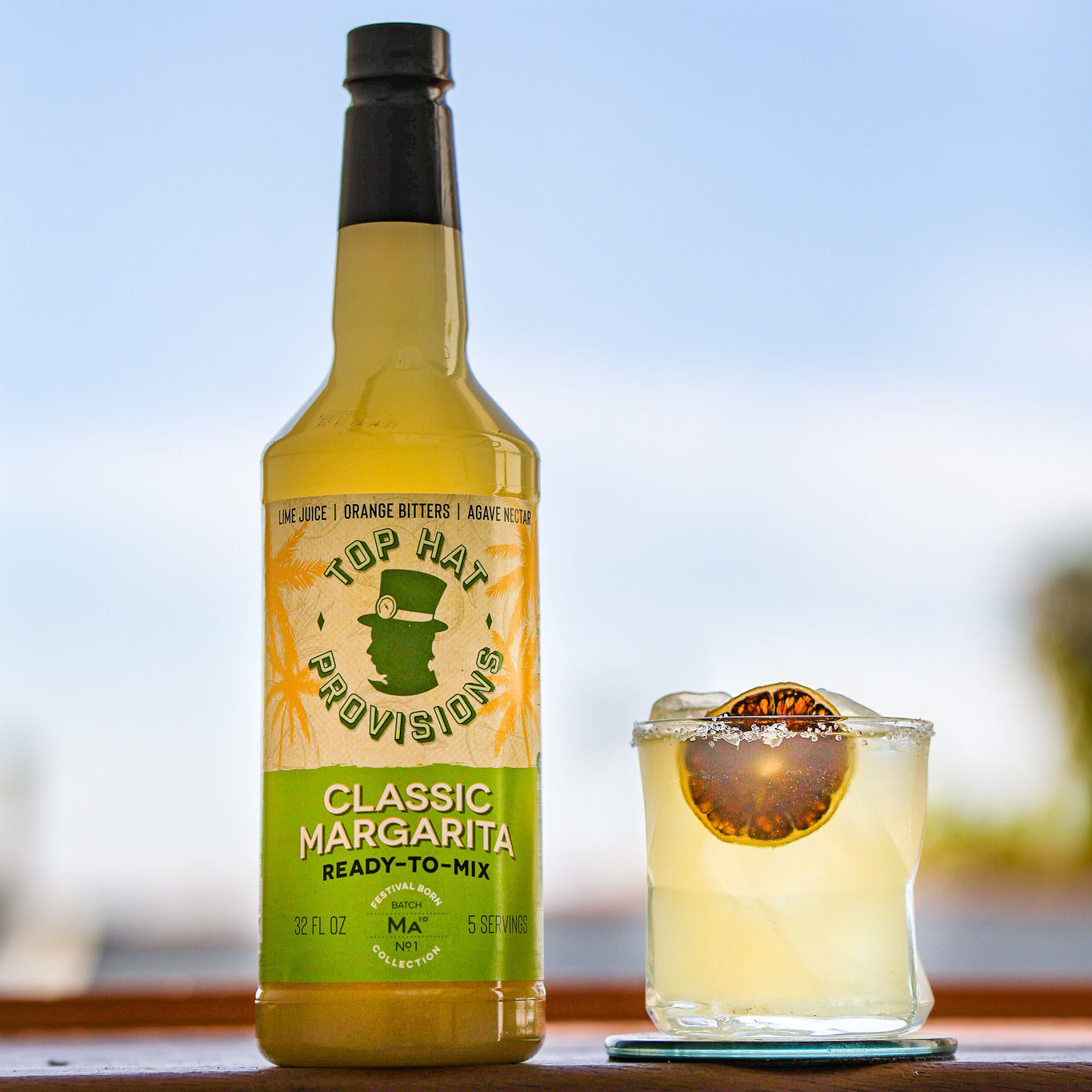 Classic margarita bottle with salted margarita on shelf, square crop