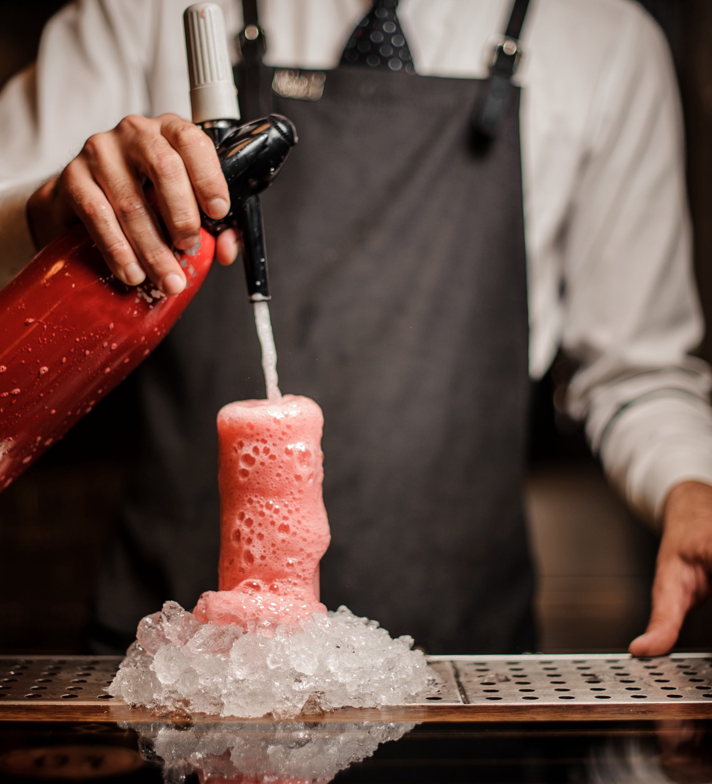 Bartender with soda siphon overflowing with Paloma