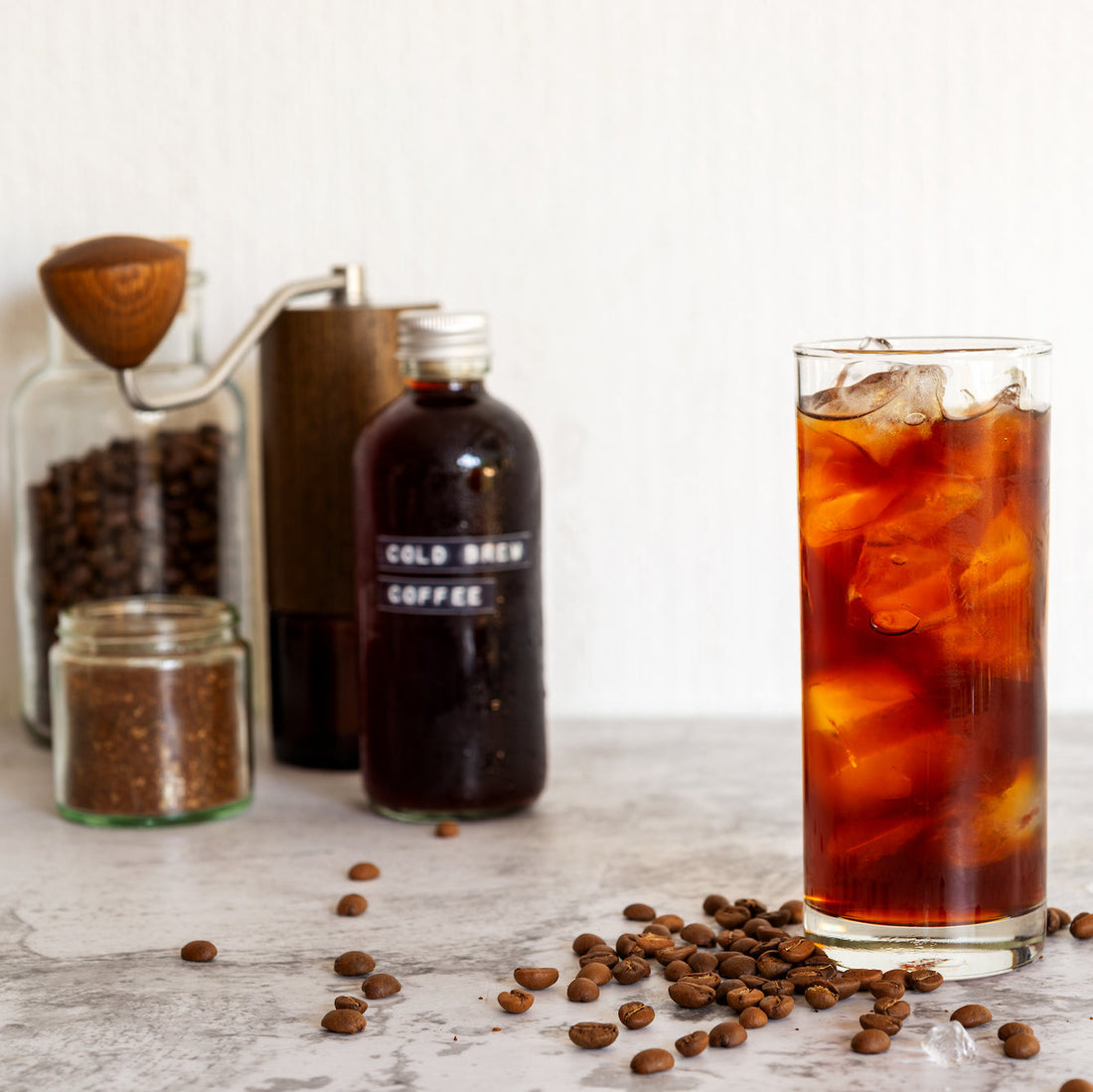 Cold brew on ice with bottle in background, square image