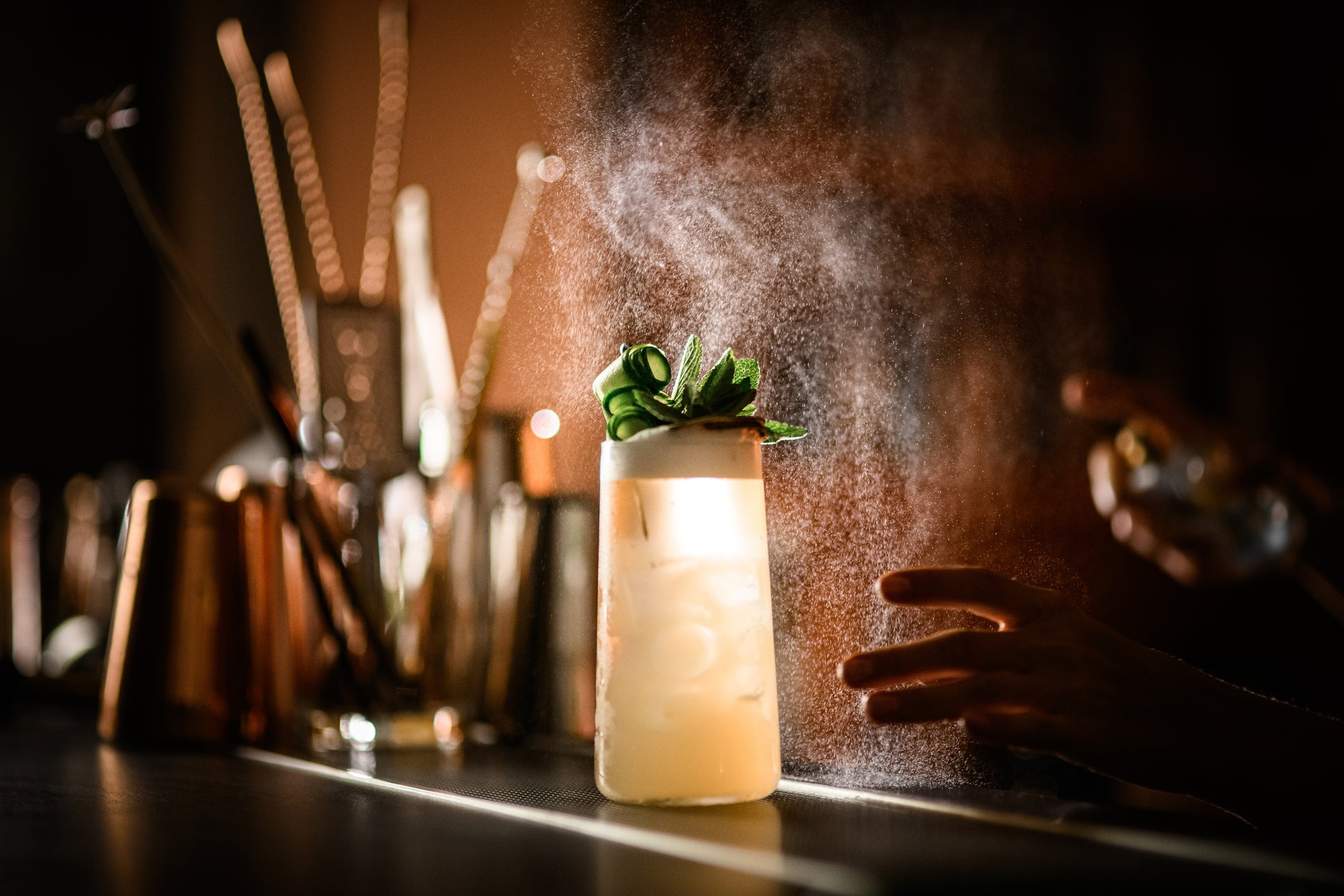 Tall mule ginger collins with mint sprigs getting misted on bar rail with tools, faded wide file